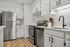 Contemporary kitchen with stainless steel appliances, white cabinetry, and wood flooring.