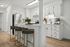 Contemporary kitchen with white cabinets, stainless steel appliances, and a stylish breakfast bar with modern stools.