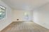Sunlit room with clean carpeting and large windows, offering a serene living environment.