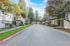 Charming tree-lined residential street with modern townhouses on either side.
