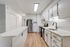 Bright modern kitchen with white cabinetry, stainless steel appliances, and wood flooring.