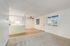 Bright open-concept living space with a modern kitchen, plush carpet, and large windows.