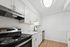 Contemporary kitchen with white cabinetry, stainless steel appliances, and wooden flooring.