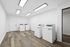 Bright and spacious laundry room equipped with multiple washing machines and dryers on wooden flooring.