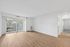 Sunlit living area with wooden flooring and large glass doors opening to a serene view.
