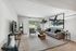 Elegant living room with modern furniture, a large abstract painting, and ample natural light.