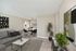 Contemporary living room with stylish decor, a gray couch, abstract art, and a view into the dining area.