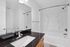 Elegant bathroom featuring a sleek granite countertop, modern fixtures, and a pristine white bathtub.