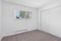Bright, minimalist bedroom featuring a large window with blinds and cozy carpet flooring.