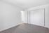 Bright, empty bedroom with plush carpet, white walls, and a large sliding closet.