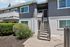 Stylish gray and white apartment exterior with a welcoming staircase and lush greenery.
