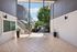 Inviting open-air corridor with tiled flooring and potted plants leading to garden and stair access.