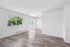 Sunlit, open-concept living area with large windows and stylish laminate flooring.