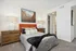 Cozy bedroom with an orange headboard, geometric artwork, and modern decor.