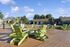 Inviting outdoor lounge area with green chairs surrounding a fire pit, set against a backdrop of mountains and blue sky.