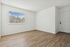 Inviting empty room with large window and elegant wooden flooring.