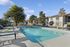 Inviting outdoor pool area with lounge chairs and lush greenery under a clear blue sky.