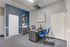 Sophisticated office interior with sleek desk, blue chairs, and abstract artwork on a two-tone wall.