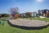 Inviting playground with slide and swings, set in a green communal area with apartment buildings in the background.