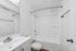 Modern bathroom with pristine white fixtures, large mirror, and bathtub.
