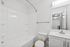 Contemporary bathroom with sleek white fixtures, a bathtub, and a vanity with a mirror.
