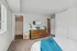 Bright and inviting bedroom with a modern wooden dresser, plush carpet, and a view into a connected bathroom.