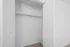 Minimalistic open closet with white sliding doors and ample hanging space.