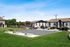 A scenic view of a modern apartment complex featuring landscaped grounds, parked cars, and surrounding greenery.