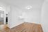 Bright and modern open space with wood flooring, white walls, and a cozy kitchen nook.