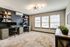 Bright home office with dual workstations, built-in shelving, and large windows.