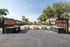 Inviting outdoor BBQ and picnic area with grills and picnic tables set against a backdrop of lush trees and residential buildings.
