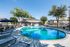 Serene outdoor pool surrounded by lounge chairs, umbrellas, and lush greenery.