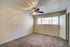 Bright bedroom with plush carpet, ceiling fan, and natural light from large window.
