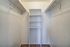 Bright walk-in closet with shelves and hanging rods, ideal for organized storage.