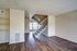 Open living space with modern staircase and hardwood floors, featuring bright windows and built-in shelving.