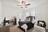 Inviting bedroom featuring a large bed with decorative pillows, a workspace with a desk and chair, and a trendy ceiling fan.