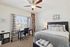 Inviting bedroom with plush bed, desk by the window, and stylish decor.