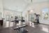 Spacious gym facility with high ceilings, equipped with treadmills, weight machines, and bright natural lighting.
