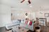 Modern living room with a stylish L-shaped sofa, vibrant cushions, and an open kitchen area.