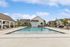 Inviting community swimming pool surrounded by comfortable lounge chairs, set in a picturesque suburban neighborhood.