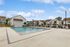 Inviting community pool surrounded by modern townhouses under a clear blue sky.