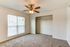 Inviting bedroom featuring soft carpet flooring, large window with blinds, and spacious open closet.