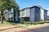 Modern two-story apartment building with a stylish facade and lush landscaping.