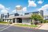 Beautifully landscaped apartment complex with modern architecture and a leasing office under a clear blue sky.