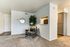 Inviting corner with a plush armchair, stylish decor, and a glimpse into a modern kitchen.