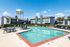 Inviting apartment complex with a large swimming pool, surrounded by modern two-story buildings and outdoor seating.