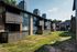 Exterior view of a stylish apartment complex with wood-paneled balconies and spacious green courtyard.