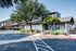 Modern apartment complex exterior with lush greenery and ample parking space.