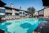Inviting apartment complex with a large swimming pool surrounded by lounge chairs and umbrellas.