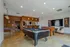 Stylish game room featuring a pool table, foosball, ping pong table, and modern seating area.